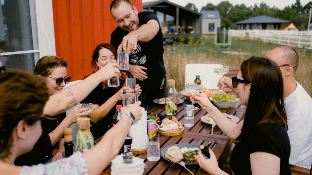 A joyful outdoor gathering with friends clinking glasses over a shared meal.