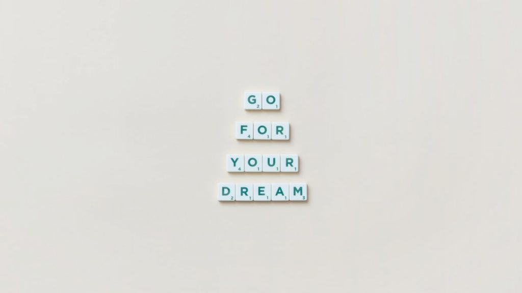 Inspirational text 'Go For Your Dream' made from Scrabble tiles on a plain background.